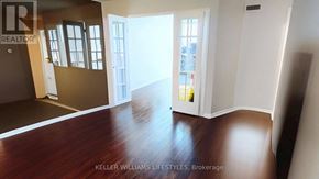 London East (East F) condo for rent - A room with a wooden floor and a doorway leading to another room.
