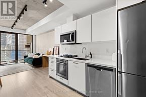 Toronto (Moss Park) condo for rent - A modern kitchen with white cabinets and stainless steel appliances.