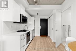 Toronto (Moss Park) condo for rent - A modern kitchen with white cabinets and a black door.