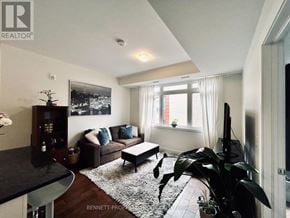 Ottawa condo for rent - A living room with a couch, a coffee table, and a television.