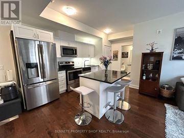 Ottawa condo for rent - A modern kitchen with a stainless steel refrigerator and a black countertop.