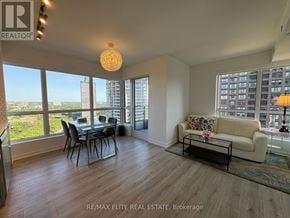 Toronto (North St. James Town) condo for rent - A spacious living room with a dining table and chairs, a sofa, and a view of the city.
