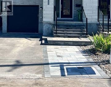 Ottawa apartment for rent - A white house with a black garage door and a stone walkway leading to the front door.