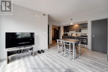 Waterloo condo for rent - A modern living room with a television and a kitchen area in the background.