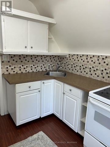 St. Catharines (Fairview) duplex for rent - A kitchen with white cabinets and a tiled backsplash.