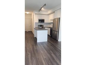 Surrey apartment for rent - A kitchen with a refrigerator, microwave, and stove top oven.