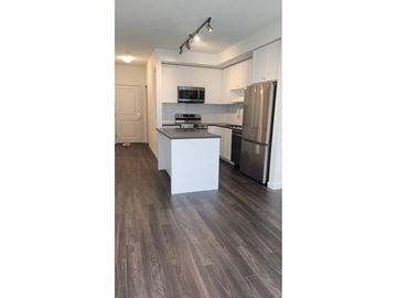 Surrey apartment for rent - A kitchen with a refrigerator, microwave, and stove top oven.