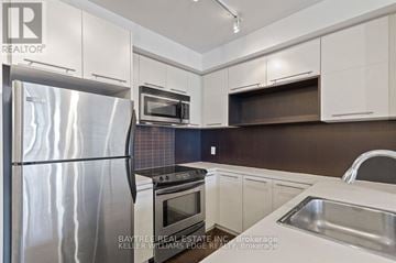 Toronto (Church-Yonge Corridor) condo for rent - A modern kitchen with a stainless steel refrigerator and white cabinets.