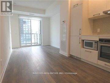 Toronto (Waterfront Communities) condo for rent - A well-lit kitchen with wooden floors and modern appliances.