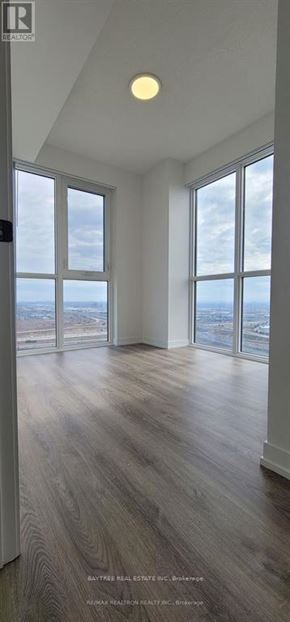 Vaughan (Vaughan Corporate Centre) condo for rent - A spacious room with wooden floors and large windows overlooking the city.
