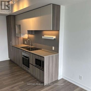 Vaughan (Vaughan Corporate Centre) condo for rent - A modern kitchen with wooden cabinets and a dark countertop.