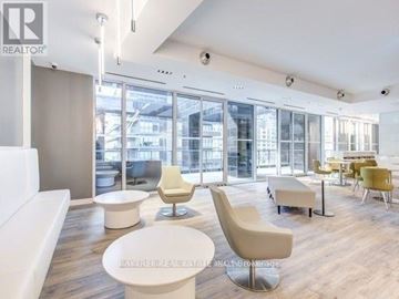 Toronto (Moss Park) condo for rent - A modern living room with white furniture and a view of the city through large windows.