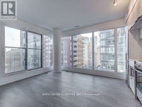 Toronto (Moss Park) condo for rent - A spacious, empty room with large windows overlooking a cityscape.