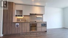 Vaughan (Vaughan Corporate Centre) condo for rent - A kitchen with wooden cabinets and a countertop with a microwave and oven.
