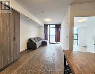 Toronto (Bay Street Corridor) condo for rent - A spacious living room with a grey sofa and wooden flooring.