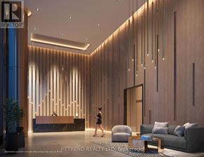 Toronto (Waterfront Communities) condo for rent - A woman walks through a modern lobby with a reception desk and a large abstract art piece on the wall.
