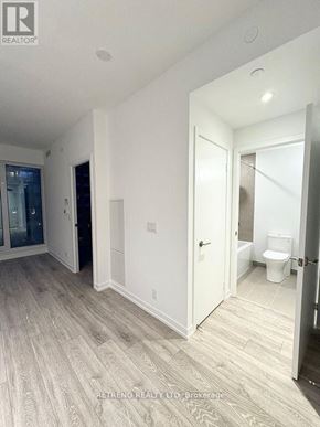 Toronto (Waterfront Communities) condo for rent - A white bathroom with wood flooring and a toilet in the corner.