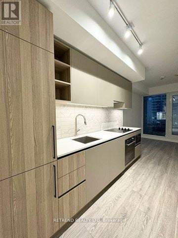 Toronto (Waterfront Communities) condo for rent - A modern kitchen with wooden cabinets and a white countertop.
