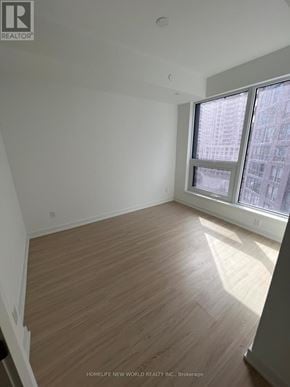 Toronto (Bay Street Corridor) condo for rent - A room with wooden flooring and a window showing a city view.