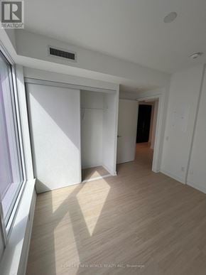 Toronto (Bay Street Corridor) condo for rent - A room with wooden flooring and white walls, with a window on the left side.