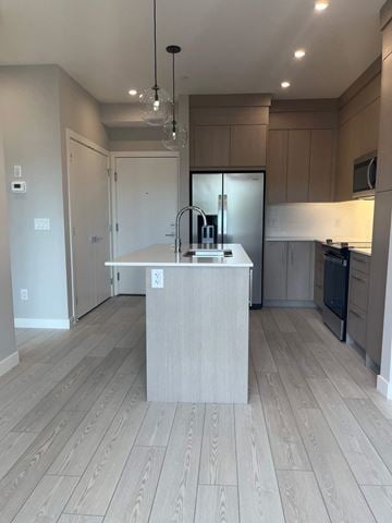 Calgary apartment for rent - A kitchen with a wooden floor and a white island in the middle.