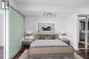 Toronto (Niagara) condo for rent - A bedroom with a bed, two lamps, and a painting on the wall.