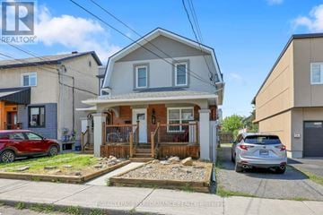 Ottawa triplex for rent - A house with a red car parked in front and a silver car parked in the driveway.