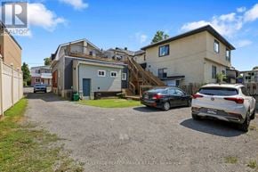 Ottawa triplex for rent - A gravel driveway leads to a two-story house with a garage.