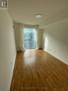 Toronto (Niagara) condo for rent - A room with wooden flooring and a window with white curtains.