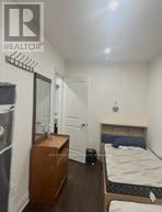 Toronto (Oakridge) apartment for rent - A bedroom with a bed, dresser, and a fridge.