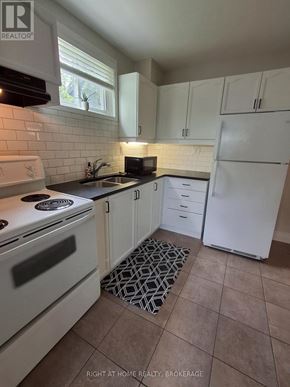 St. Catharines (Port Dalhousie) duplex for rent - A kitchen with white appliances and a black and white rug on the floor.