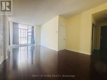 Mississauga (City Centre) condo for rent - A room with wooden floors and white walls, with a door on the right side.