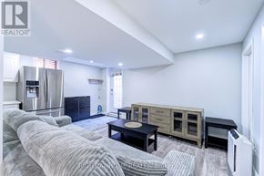 Mississauga (Lisgar) apartment for rent - A well-lit, spacious living room with a grey sofa, wooden coffee table, and a stainless steel refrigerator.