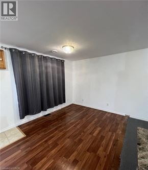 Fort Erie apartment for rent - A room with wooden flooring and a window with grey curtains.
