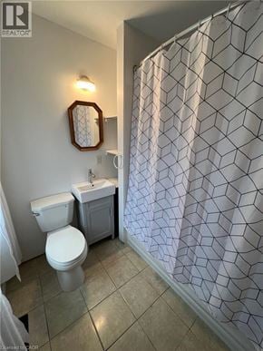 Fort Erie apartment for rent - A bathroom with a toilet, sink, and shower curtain.