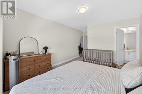 Brantford apartment for rent - A bedroom with a white bed, a dresser, and a mirror.
