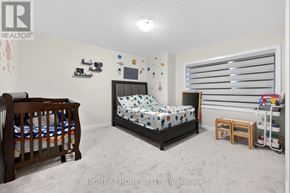 Brantford apartment for rent - A bedroom with a bed, a crib, and a window with blinds.