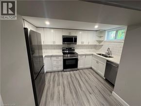 Kitchener apartment for rent - A modern kitchen with white cabinets and a wooden floor.
