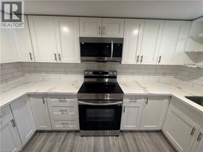 Kitchener apartment for rent - A kitchen with white cabinets and a black stove top oven.