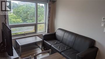 Waterloo condo for rent - A black leather couch sits in a living room with a coffee table in front of it.