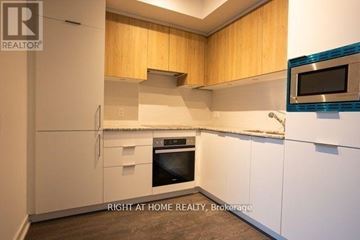 Toronto (Banbury-Don Mills) condo for rent - A kitchen with white cabinets and a microwave above the stove.
