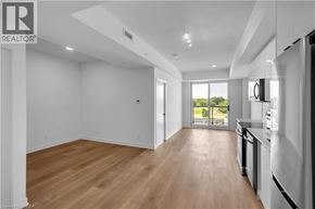 Brantford condo for rent - A spacious, empty room with wooden floors and white walls.