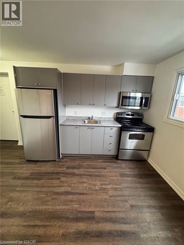 Kitchener apartment for rent - A kitchen with a refrigerator, oven, and microwave.