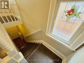 Toronto (High Park-Swansea) apartment for rent - A staircase with a wooden handrail and a glass window with a rose design.
