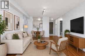 Toronto (Newtonbrook East) condo for rent - A living room with a white couch, wooden chairs, and a flat screen TV.