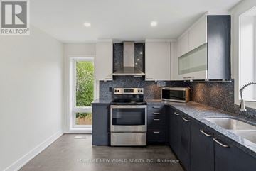 Toronto (Greenwood-Coxwell) apartment for rent - A modern kitchen with a stove top oven and microwave.