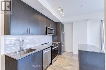 Oakville (Jm Joshua Meadows) condo for rent - A modern kitchen with dark wood cabinets and stainless steel appliances.