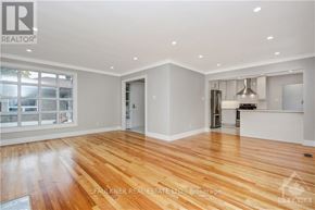 Ottawa apartment for rent - A spacious room with wooden flooring and a kitchen area in the background.