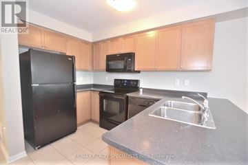 Milton (Sc Scott) townhouse for rent - A kitchen with black appliances and wooden cabinets.