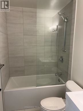 Brantford condo for rent - A white toilet sits next to a glass shower stall.
